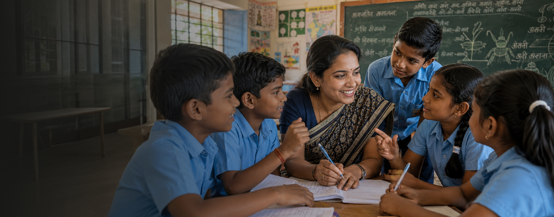Teacher engaging with students around a classroom desk