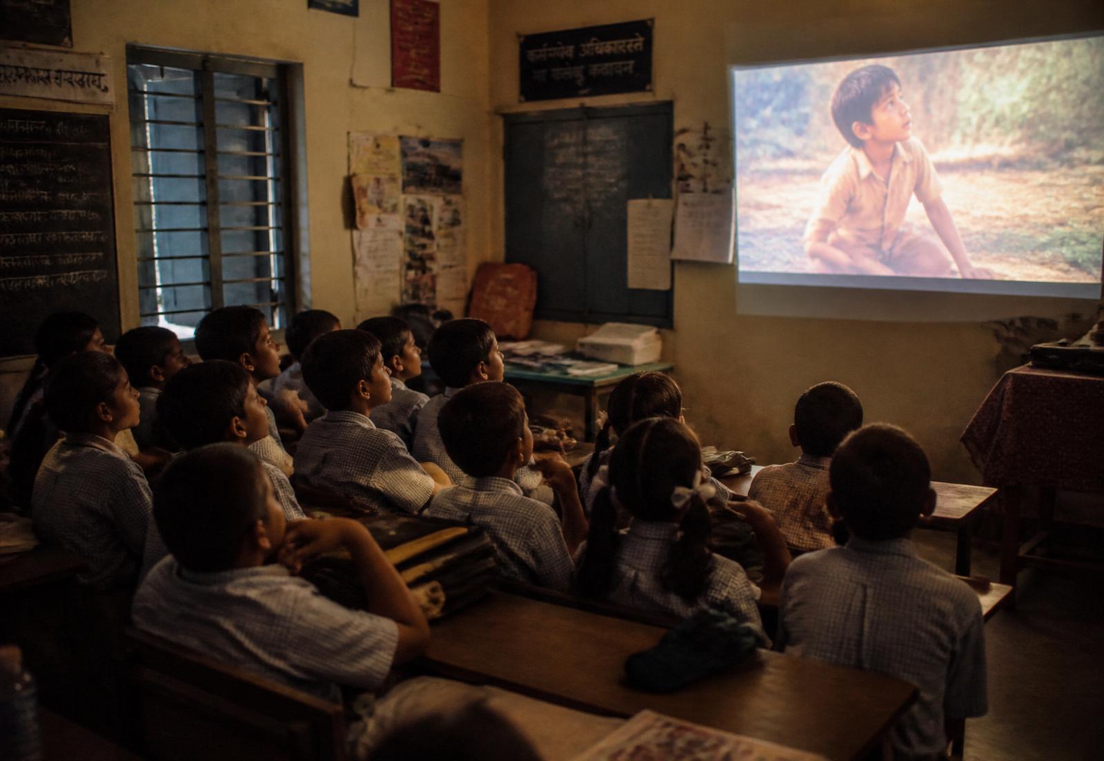 Children watching a film projected on a classroom wall