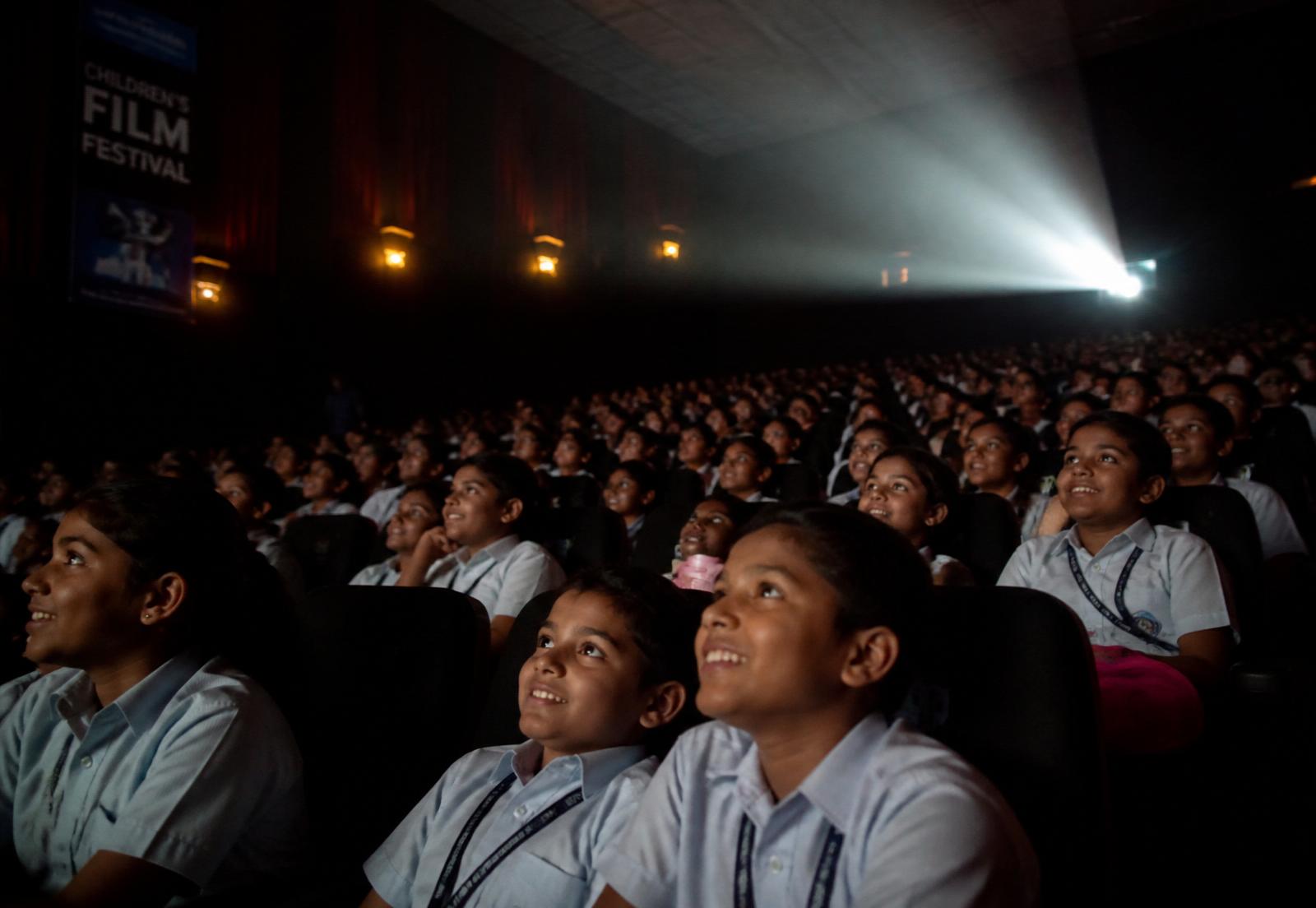 Children watching a film in a packed cinema hall